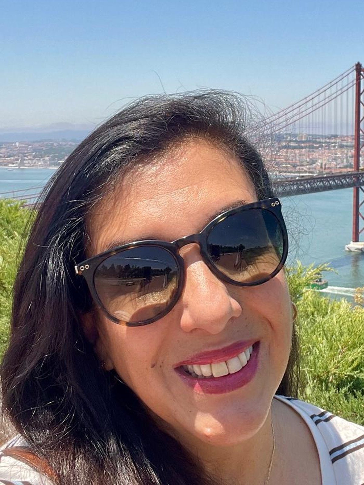 Valéria Januzzi, guia turística brasileira em Lisboa, com a Ponte 25 de Abril ao fundo